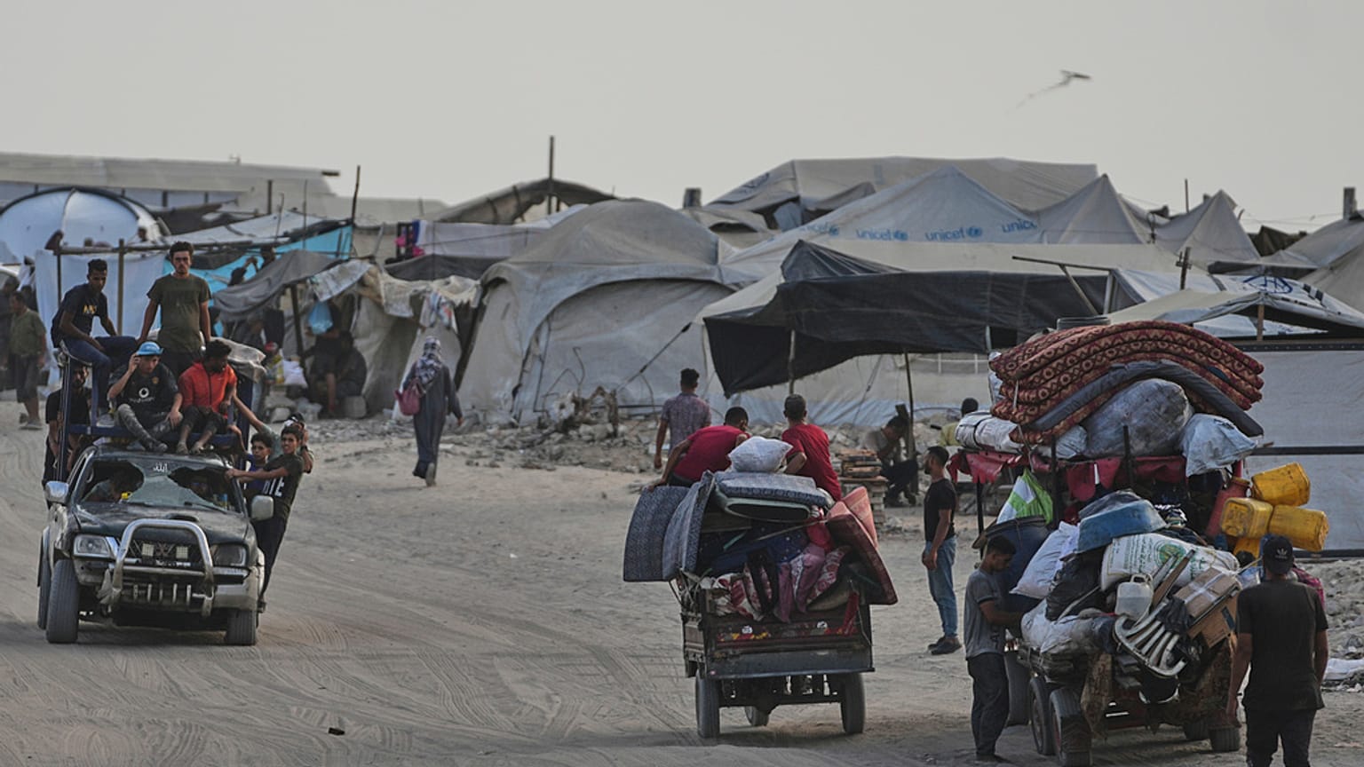 فلسطينيون ينقلون ممتلكاتهم قرب مخيم نزوح على شاطئ مدينة غزة، بتاريخ 10 أغسطس 2025.