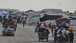 فلسطينيون ينقلون ممتلكاتهم قرب مخيم نزوح على شاطئ مدينة غزة، بتاريخ 10 أغسطس 2025.