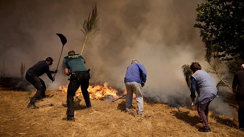 Moradores combatem um incêndio florestal que avança em direção à aldeia de Rebordondo, perto de Ourense, no noroeste de Espanha, 18 de agosto de 2025.