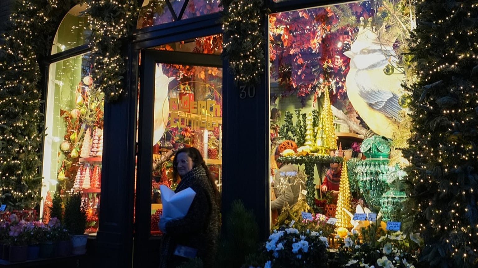 A woman walks out of a florist shop with a window display for the holidays, in Antwerp, Belgium, Monday, Dec. 22, 2025.