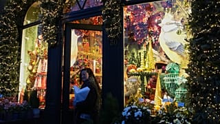 A woman walks out of a florist shop with a window display for the holidays, in Antwerp, Belgium, Monday, Dec. 22, 2025.