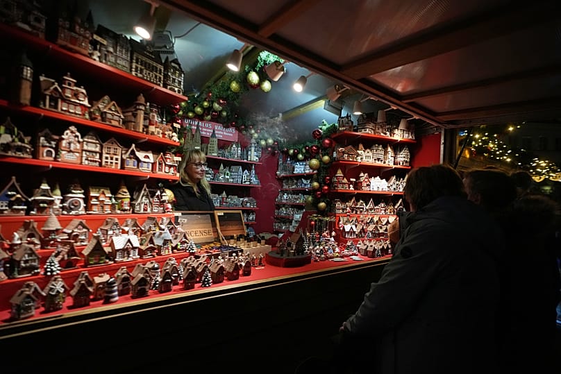 Two women shop in a traditional wooden hut at a Christmas market in the historical center of Antwerp, Belgium, Friday, Dec. 12, 2025.