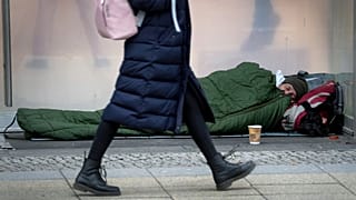 Obdachloser Mann liegt in einem Schlafsack auf der Einkaufsstraße Kurfürstendamm, Berlin, 1. Februar 2022