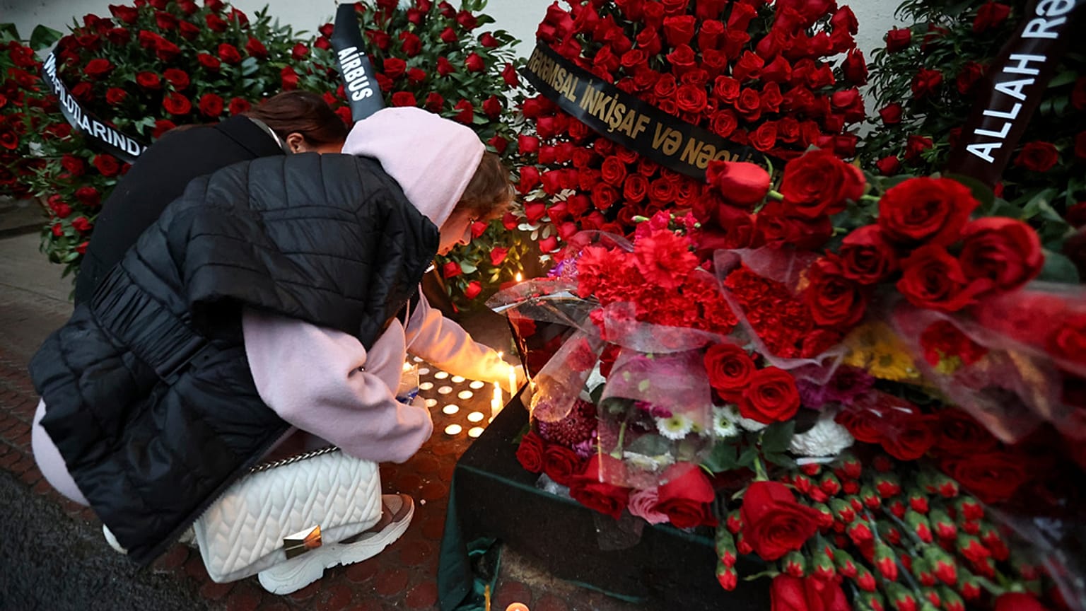 FILE: A woman lights candles at the wall of the apartment building in Baku, in memory of pilot Alexander Kalyanin, who died in the Azerbaijan Airlines crash, 28 December 2024