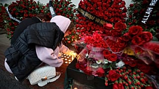 FILE: A woman lights candles at the wall of the apartment building in Baku, in memory of pilot Alexander Kalyanin, who died in the Azerbaijan Airlines crash, 28 December 2024