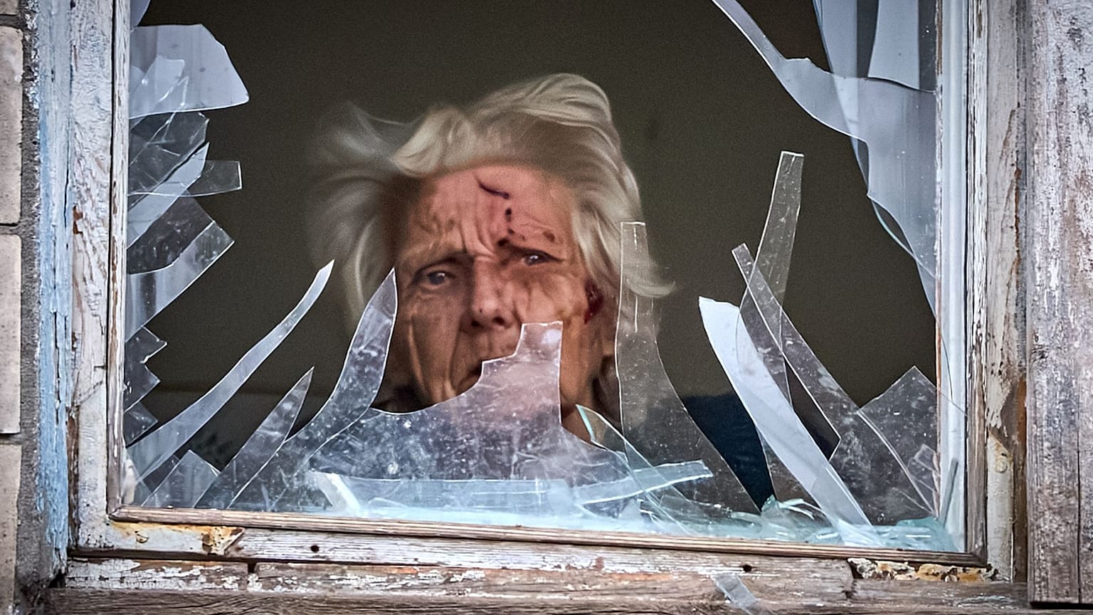 یک زن سالمند مجروح از پنجره شکسته آپارتمان خود به بیرون نگاه می‌کند؛ ساختمانی که روز سه‌شنبه ۲۳ دسامبر ۲۰۲۵، در جریان یک حمله هوایی در کی‌یف، اوکراین، هدف پهپاد روسیه قرار گرف