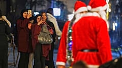 رهگذران در دمشق پیش از تعطیلات کریسمس از دو مرد با لباس سانتا کلوز عکس می‌گیرند