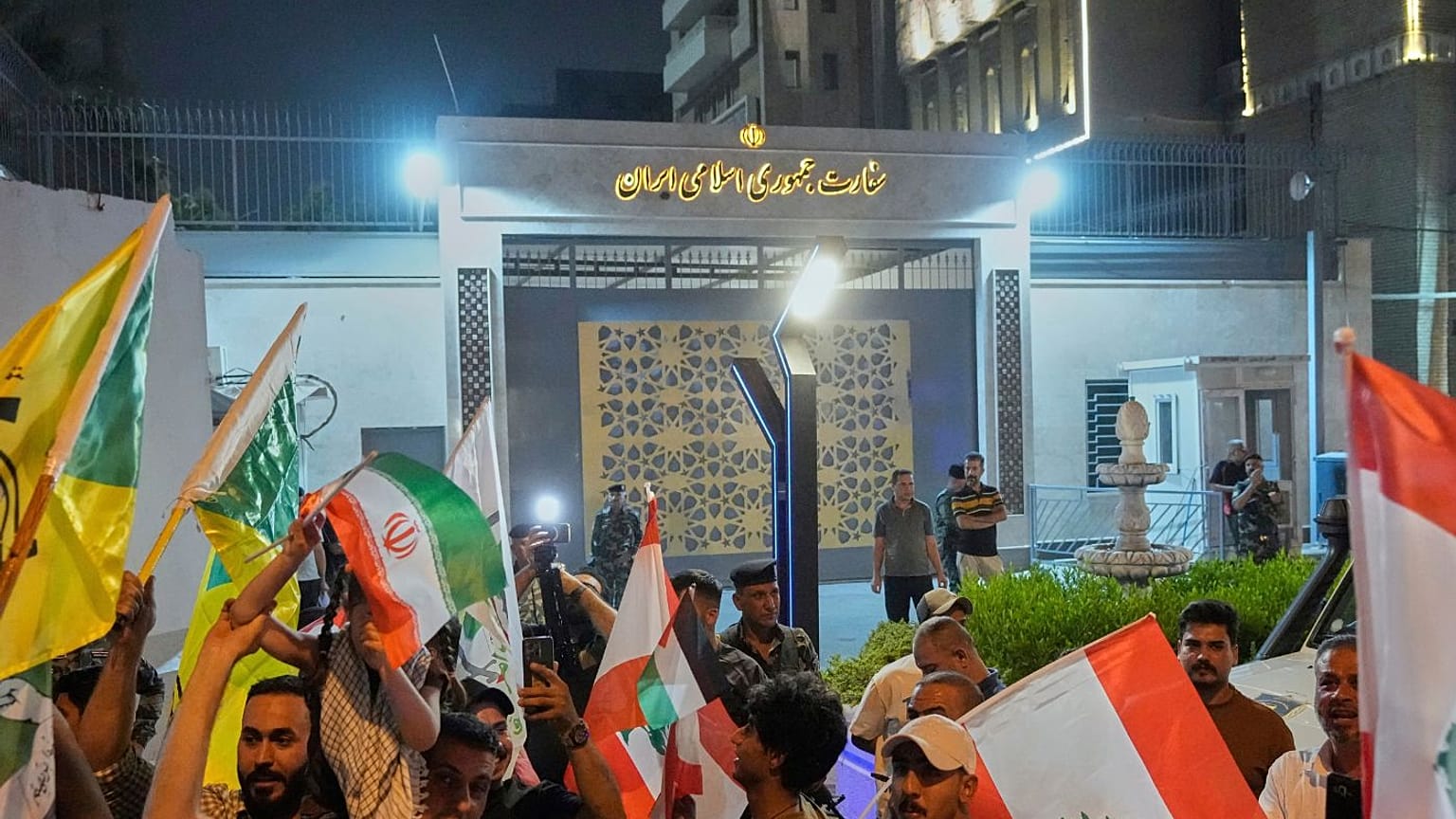 گروهی از طرفداران جمهوری اسلامی در مقابل سفارت ایران، پرچم لبنان و ایران را در دست دارند