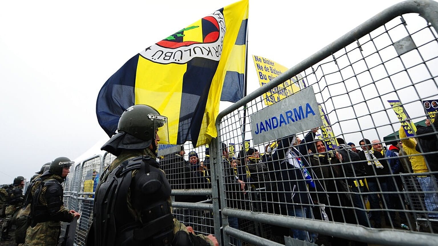 ARŞİV – Silivri’deki şike davasının ilk duruşması öncesinde, Aziz Yıldırım’a destek için alanda bulunan Fenerbahçe taraftarının yanından geçen bir polis. / 14 Şubat 2012 Salı