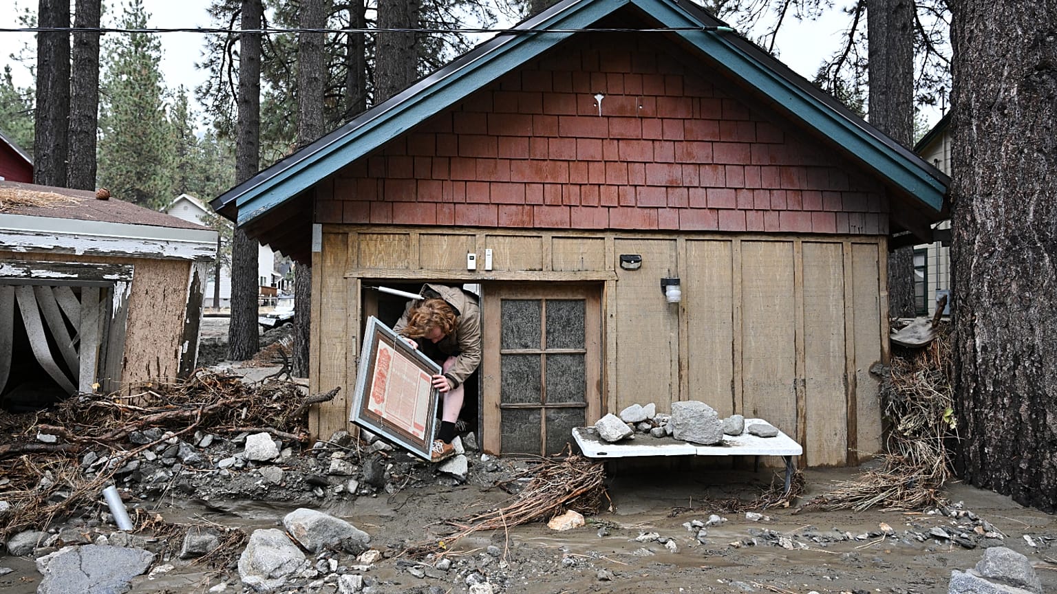 Davey Schneider recovers items from his storm damaged home, Dec. 25, 2025, in Wrightwood, California, US