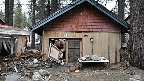 Davey Schneider ingóságokat ment ki viharkáros otthonából 2025. december 25-én, Wrightwoodban, Kaliforniában, az Egyesült Államokban.