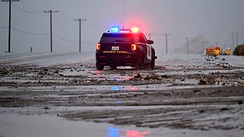 A California Highway Patrol officer drives along California State Route 138 through mud Wednesday, Dec. 24, 2025, near Wrightwood, Calif.