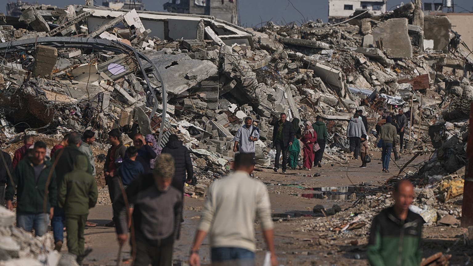 فلسطينيون يسيرون في شارع تحيط به مبانٍ مدمّرة جراء العمليات الجوية والبرية الإسرائيلية في مدينة غزة، الأربعاء 17 ديسمبر/كانون الأول 2025. (تصوير: جهاد الشرفي / أسوشيتد برس)