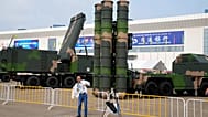 FILE: A visitor puts on his jacket, near a missile launcher displayed during the 13th China International Aviation and Aerospace Exhibition, also known as Airshow China 2021.