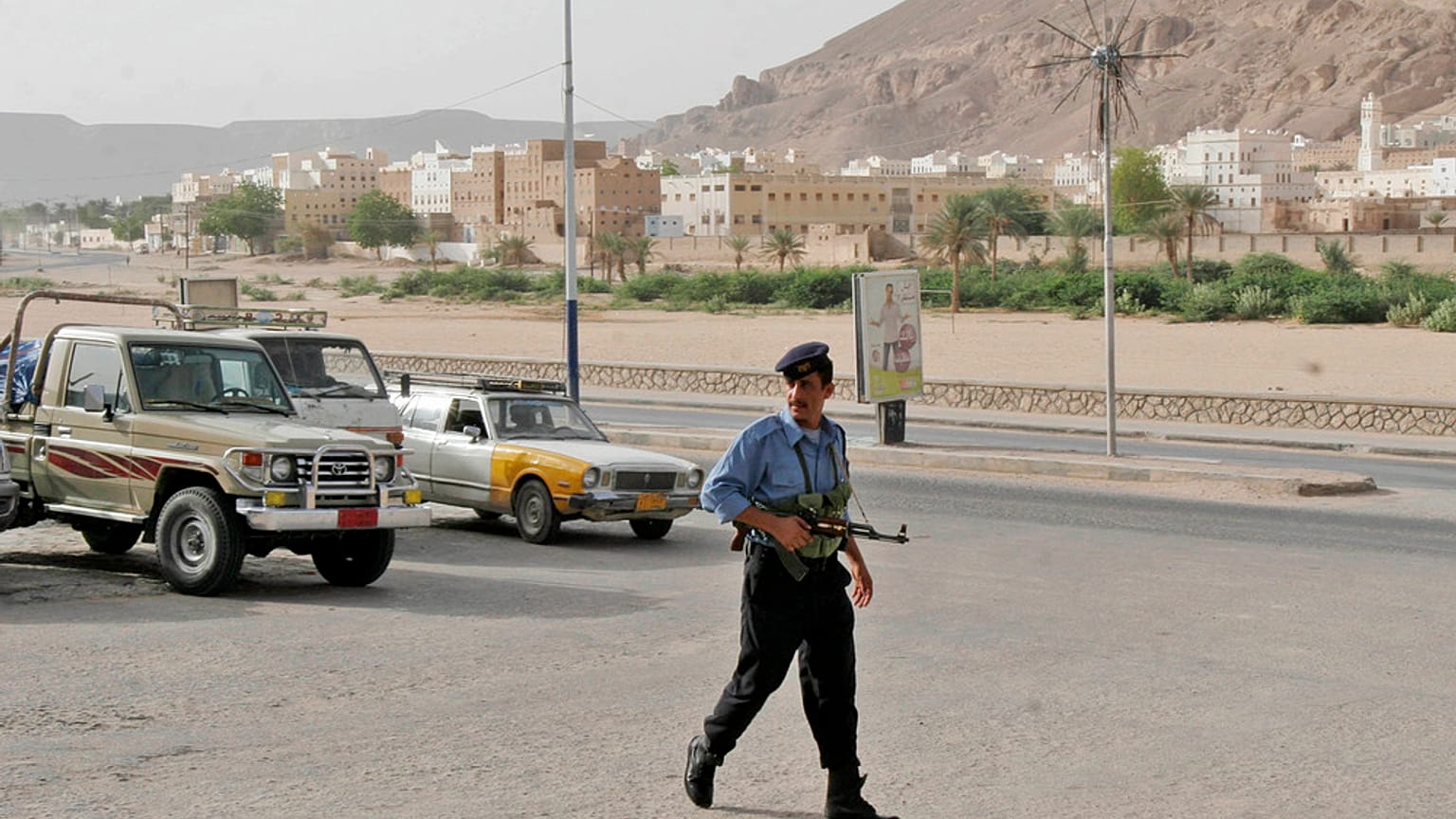 شرطي يمني مسلح يسير أمام بوابة المدينة التاريخية شبام.