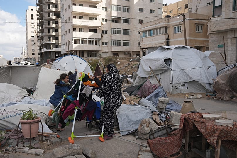 Members of the Al-Ajouri family stand by their tent that was destroyed by a strong wind and rain in Gaza City, Sunday, Dec. 28, 2025. 