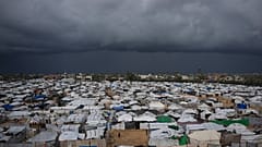 الأطفال الفلسطينيون يقفون في منطقة محاطة بخيام مؤقتة في مخيم للنازحين في دير البلح وسط قطاع غزة، يوم السبت 27 ديسمبر 2025.
