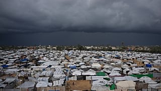 الأطفال الفلسطينيون يقفون في منطقة محاطة بخيام مؤقتة في مخيم للنازحين في دير البلح وسط قطاع غزة، يوم السبت 27 ديسمبر 2025.