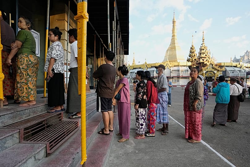 Voters line up to cast their ballots at a polling station, with Sule Pagoda in background, Sunday, Dec. 28, 2025, in Yangon, Myanmar. (AP Photo/Thein Zaw)