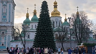 Des personnes marchent autour de l'arbre de Noël devant le monastère Sainte-Sophie dans le centre de Kiev, en Ukraine, mercredi 10 décembre 2025. 