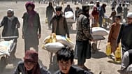 Persone trasportano sacchi e scatole di cibo e aiuti umanitari in Afghanistan