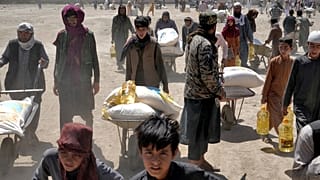 Persone trasportano sacchi e scatole di cibo e aiuti umanitari in Afghanistan