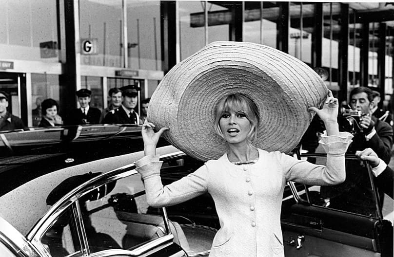 French actress Brigitte Bardot poses with a huge sombrero she brought back from Mexico, as she arrives at Orly Airport in Paris, France, on 27 May 1965