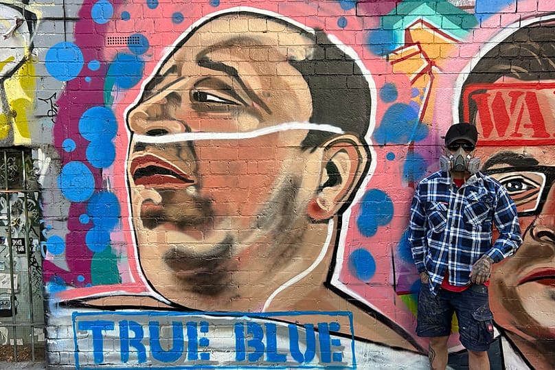 الفنان التشكيلي جارود جريش يلتقط صورة بجانب لوحته لأحمد الأحمد، في ملبورن، أستراليا، يوم الأحد 28 ديسمبر 2025.