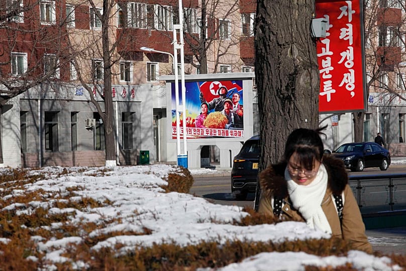 People walk in the street of the Central District of Pyongyang, 25 December, 2025 