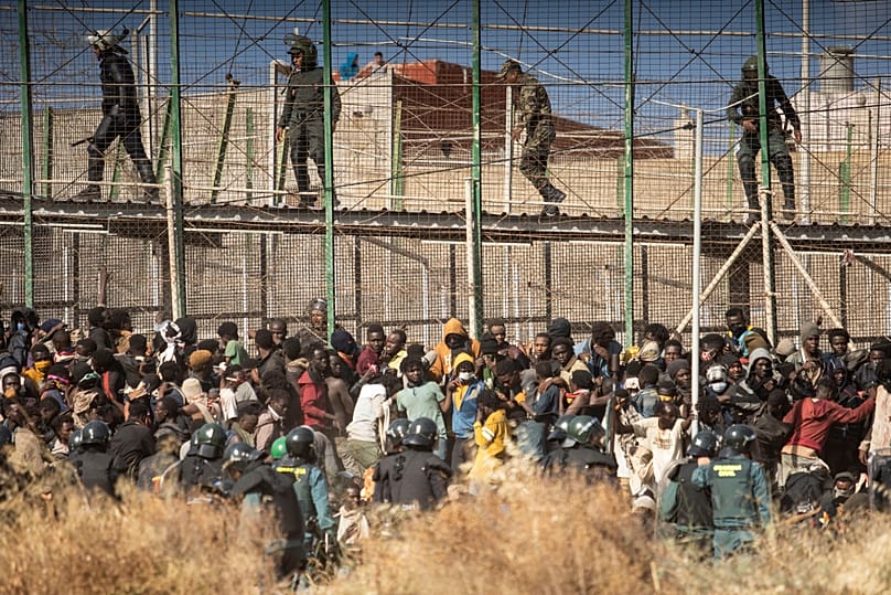 Riot police officers cordon off the area after migrants arrive on Spanish soil and crossing the fences separating the Spanish enclave of Melilla from Morocco, 24 June, 2022