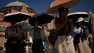 Turisták napernyőkkel védik magukat a naptól a Hagia Sophia mecset előtt egy forró nyári napon Isztambulban, 2025. augusztus 12-én.