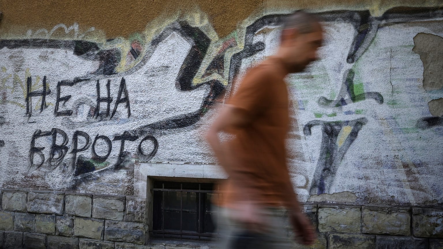 Egy férfi elhalad egy „Nem az euróra” feliratú graffiti mellett Szófiában, Bulgáriában, 2025. június 2-án.