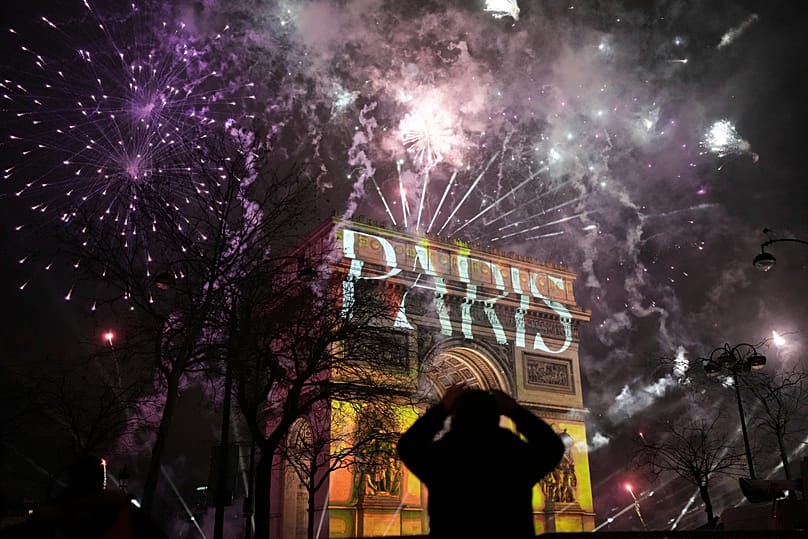 A light show is projected on the Arc de Triomphe as fireworks explode during New Year celebrations in Paris, 1 January, 2025