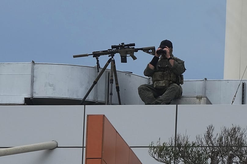 An officer sits with a firearm on the roof of a building at Bondi Beach in Sydney, 21 December 2025