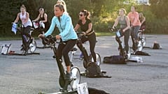 Jackie Brennan, de Merrimac, Massachusetts, delante, pedalea en una bicicleta estática con otras personas durante una clase de spinning en un aparcamiento fuera de Fuel Training Studio.