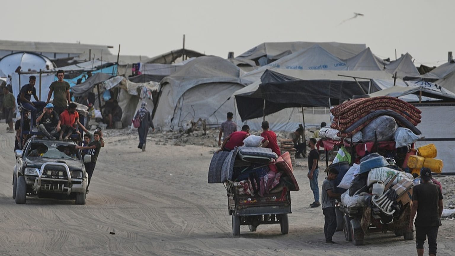 فلسطينيون ينقلون ممتلكاتهم قرب مخيم للنازحين على شاطئ مدينة غزة، في 10 أغسطس 2025.