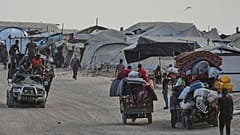 فلسطينيون ينقلون ممتلكاتهم قرب مخيم للنازحين على شاطئ مدينة غزة، في 10 أغسطس 2025.