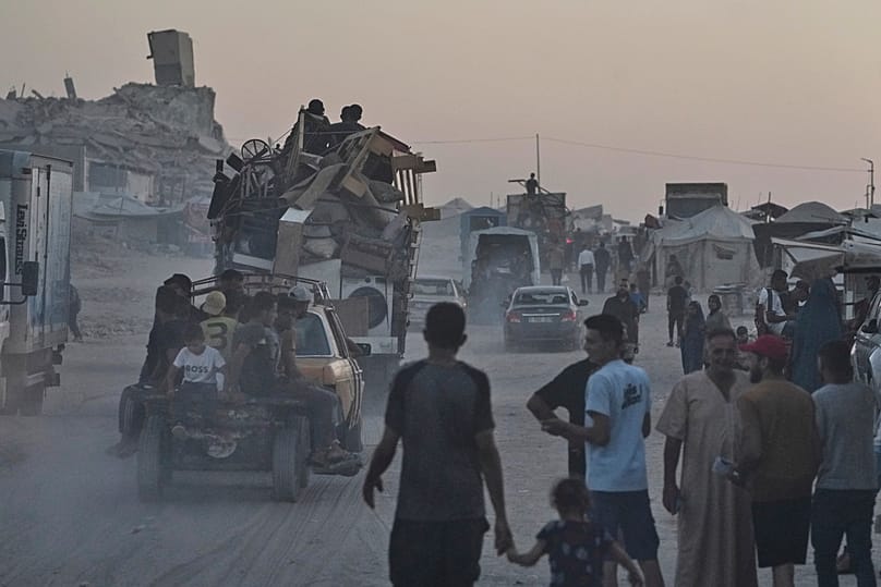 فلسطينيون ينقلون ممتلكاتهم قرب مخيم للنازحين على شاطئ مدينة غزة، في 23 أغسطس 2025.