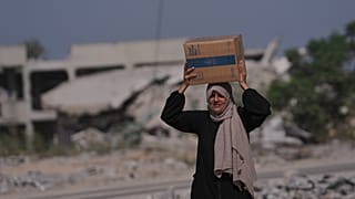 امرأة فلسطينية تحمل صندوقًا غذائيًا من برنامج الأغذية العالمي بعد تسلّمه في خان يونس جنوب قطاع غزة، في 20 أكتوبر 2025.