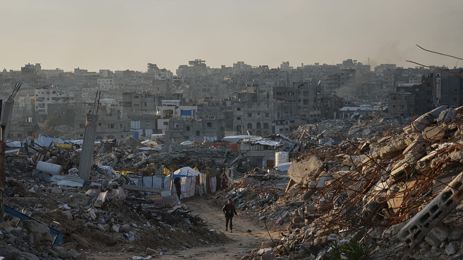 رجل فلسطيني يمشي على طريق تحيط به مبانٍ دُمرت خلال العمليات الجوية والبرية الإسرائيلية في مدينة غزة، يوم الثلاثاء، 30 ديسمبر 2025.