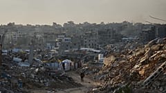 رجل فلسطيني يمشي على طريق تحيط به مبانٍ دُمرت خلال العمليات الجوية والبرية الإسرائيلية في مدينة غزة، يوم الثلاثاء، 30 ديسمبر 2025.