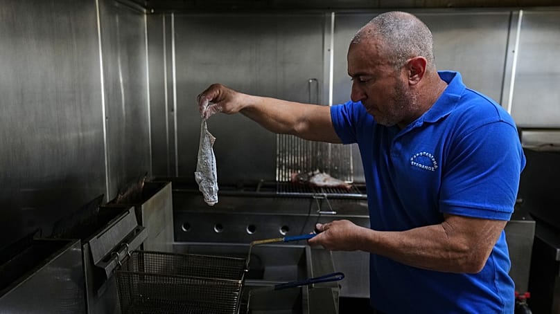Stefanos Mentonis, owner of Stefanos restaurant, cooks lionfish in Larnaca, Cyprus, in the eastern Mediterranean, Thursday, Dec. 18, 2025. 