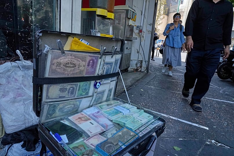 Notas de banco iranianas exibidas por um cambista de rua no centro de Teerão, 28 de agosto de 2025