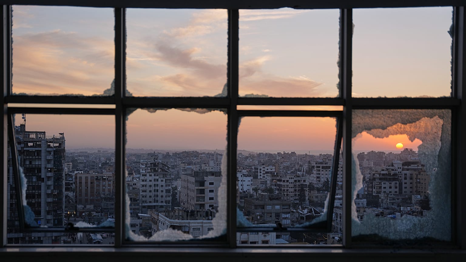 تغرب الشمس خلف مبانٍ متضررة جراء الحرب في مدينة غزة، الأربعاء، 31 ديسمبر/كانون الأول 2025.