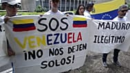 FILE - On 10 January 2019, Venezuelan citizens living in Brazil hold signs that read in Spanish "S.O.S. Venezuela. Don't leave us alone," left, and "Maduro. Illegitimate." 