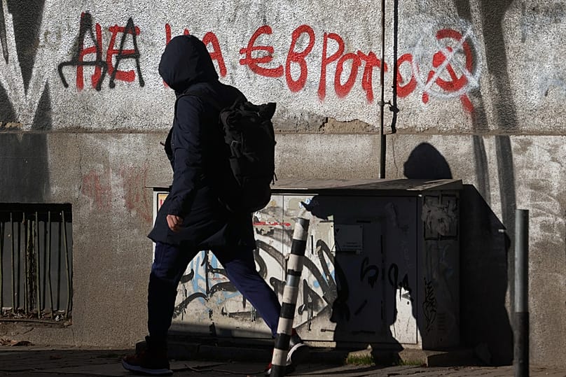 A person passes by a graffiti reading "No to the euro" altered to "Yes to the euro" in Sofia, 29 December 2025