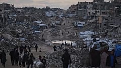 يسير فلسطينيون قرب مبانٍ مدمّرة في شمال قطاع غزة، يوم الجمعة 2 يناير/كانون الثاني 2026.