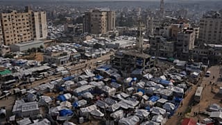 فلسطينيون يسيرون في شوارع مدينة غزة، مروراً بمخيمات الخيام للنازحين، الأربعاء 31 ديسمبر/كانون الأول 2025. (صورة من وكالة أسوشييتد برس/عبد الكريم حنا)