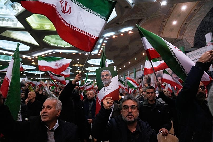 People wave Iranian flags and hold a poster of the late commander of the Iran's Revolutionary Guard expeditionary Quds Force Qassem Soleimani in Tehran, 1 January, 2026