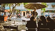 A man standing facing three women sitting at tables